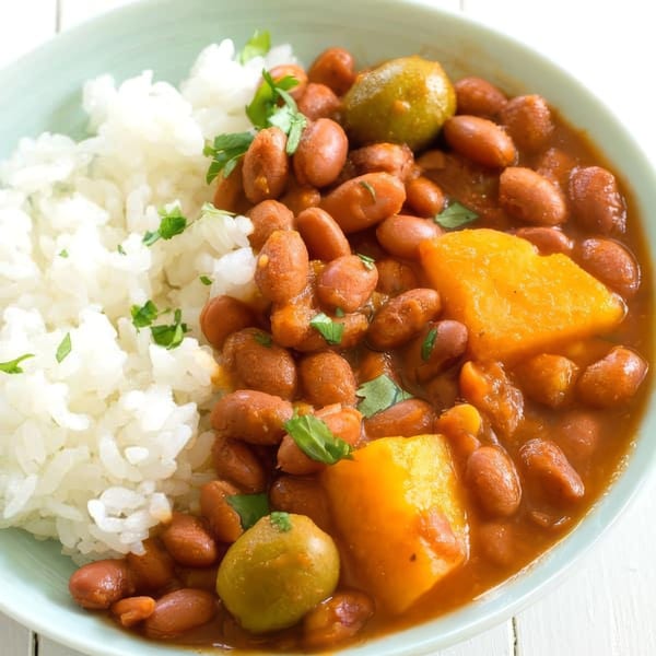 A close-up of Puerto Rican red beans with rice, green olives, and calabaza squash.