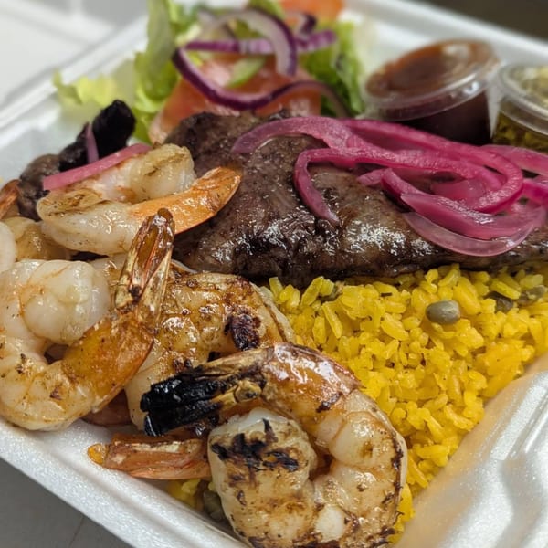Grilled shrimp and steak with yellow rice, pickled red onions, and a side salad.